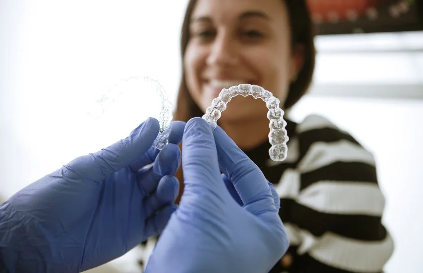 Ortodoncista mostrando un retenedor transparente a una paciente durante una revisión post-ortodoncia